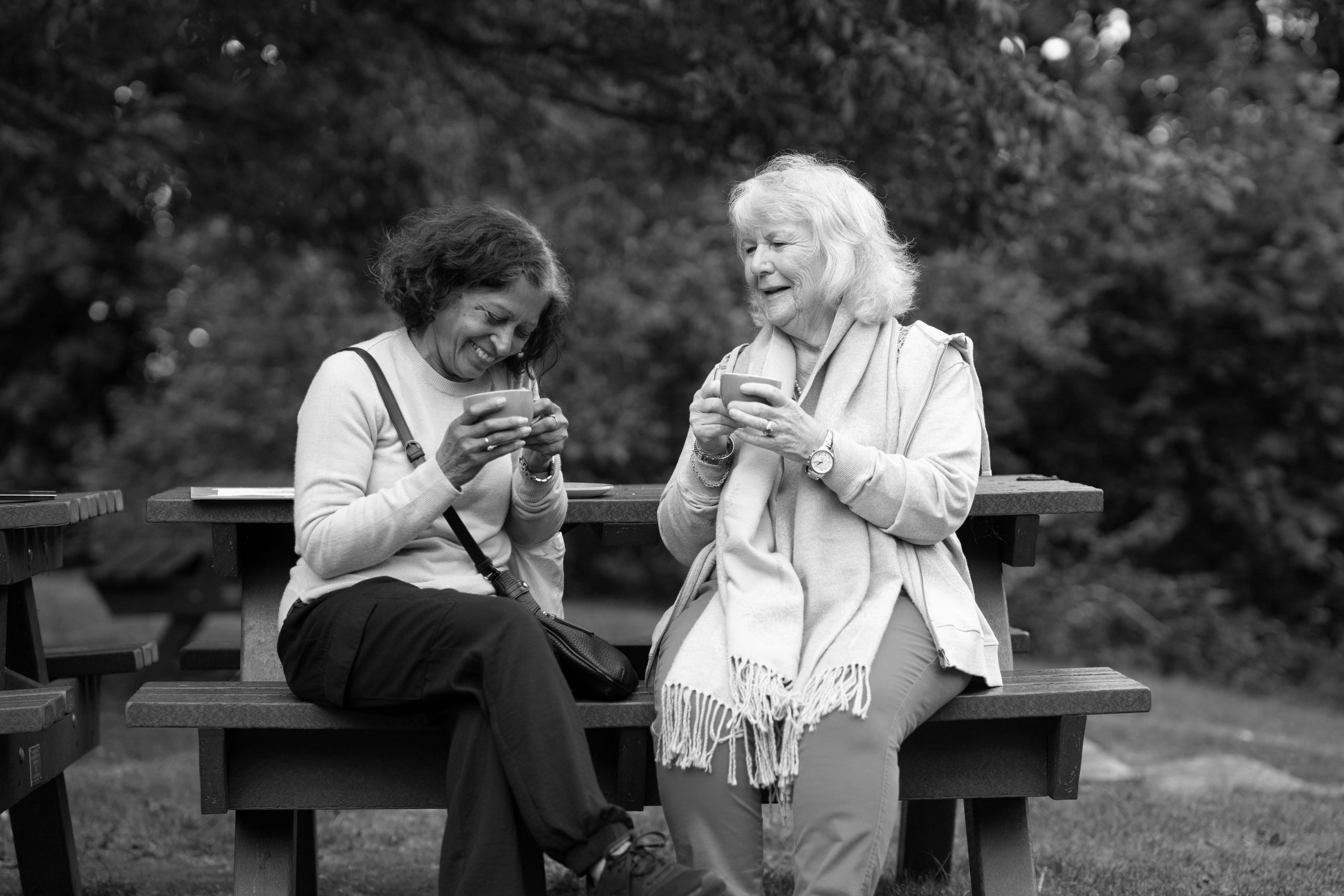 Two older women sitting on a park bench together